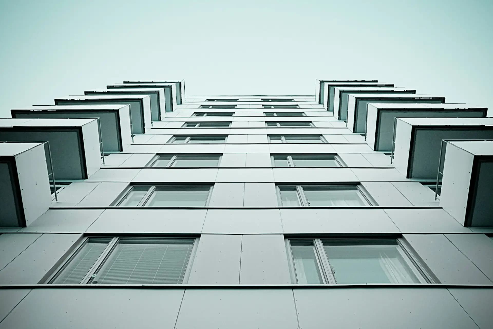 Fasad på ett modernt flerbostadshus sett underifrån, symboliserar fastighetens värde.